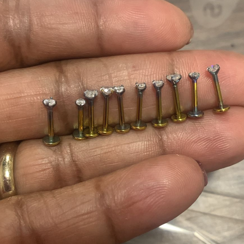 Anodized ASTM F136 titanium body jewelry pieces showing matte, dull surfaces after anodizing and sterilization, with noticeable loss of gloss and color vibrancy